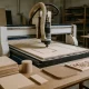 CNC router cutting different materials with projects in progress around it.